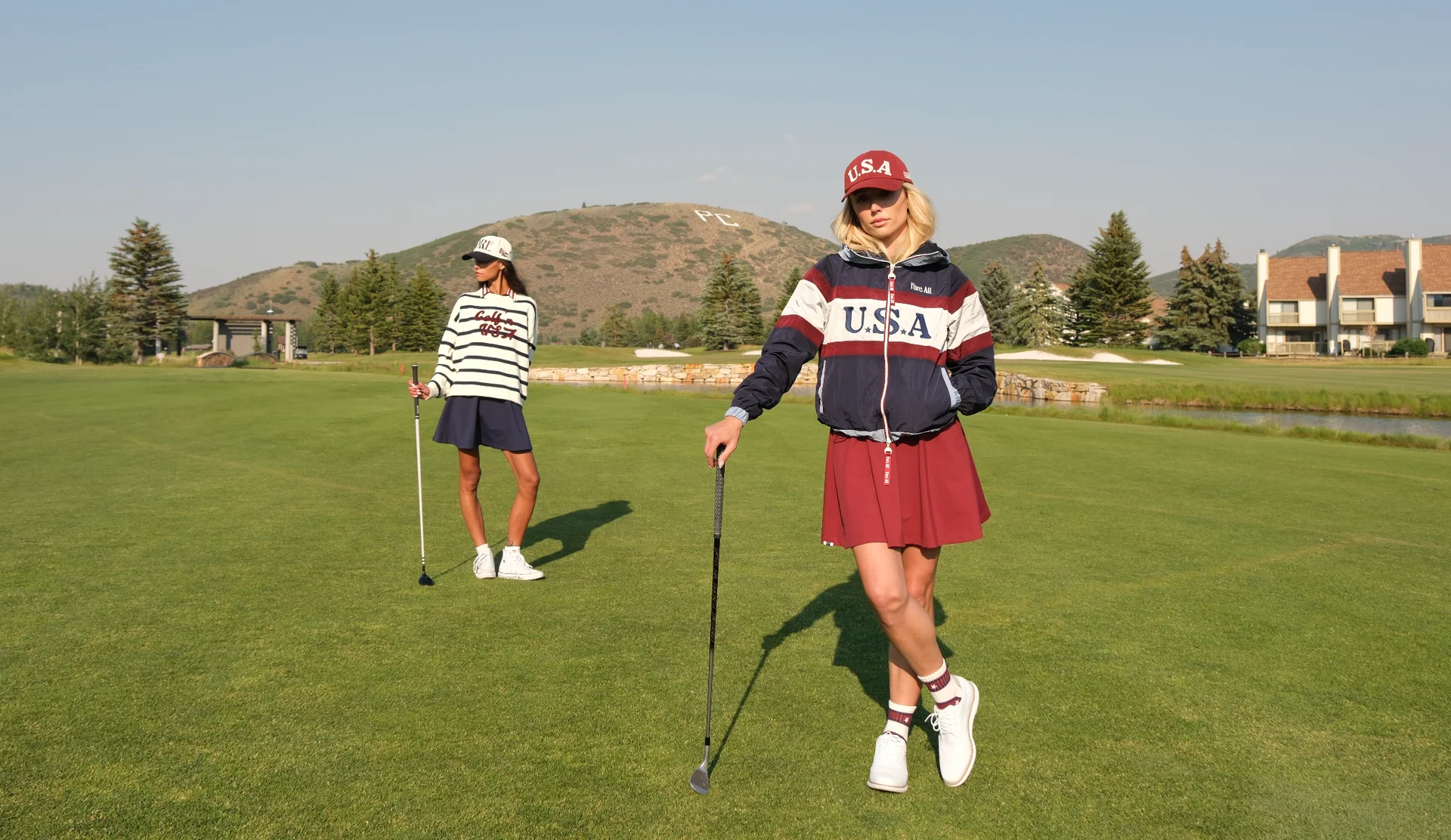 Two golfers on a sunlit fairway with rolling hills